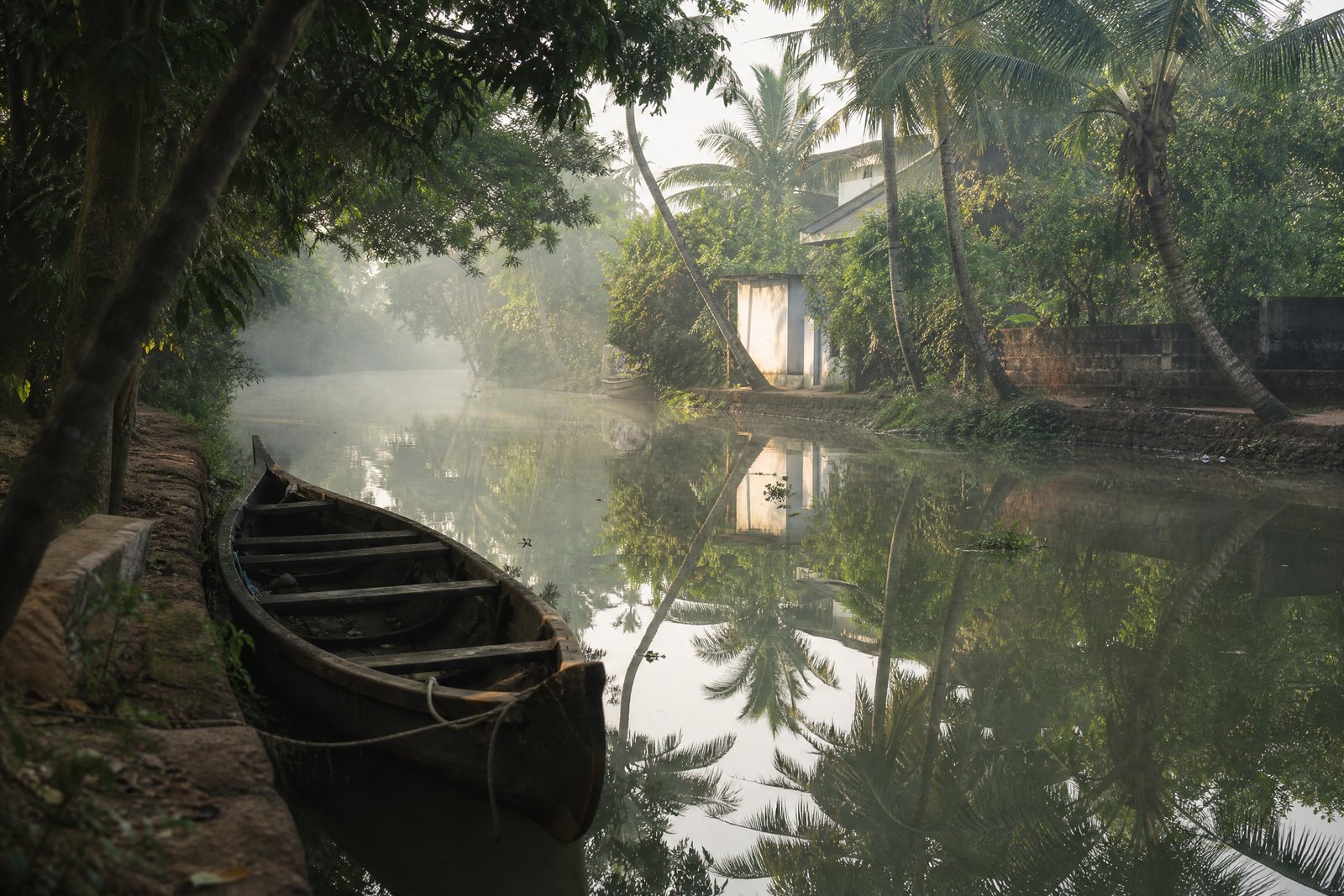 A village canoe beside a quiet palm-lined canal in Kerala